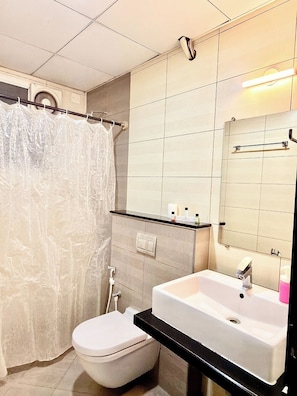 Une salle de bain Ă©quipĂ©e de toilettes, dâun lavabo, dâun rideau de douche et dâun miroir.