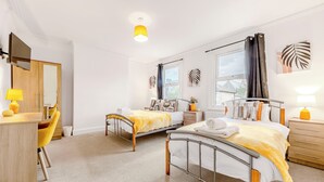Ein Hotelzimmer mit zwei Betten, einem Schreibtisch, einem Stuhl und einem Fenster.