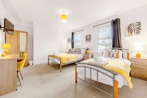 Camera d'albergo con due letti, una scrivania, una sedia e una finestra.