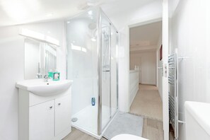 Un bagno moderno con cabina doccia in vetro, un lavandino bianco e uno specchio.