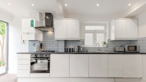 Eine moderne Küche mit weißen Schränken, einem eingebauten Backofen, einem Gasherd und einer Mikrowelle.