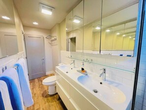 A modern bathroom with two sinks, a toilet, and a shower.