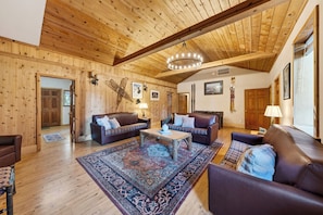 Ein Holzinnenraum mit Sofas, einem Teppich und einer Chandelüstere.