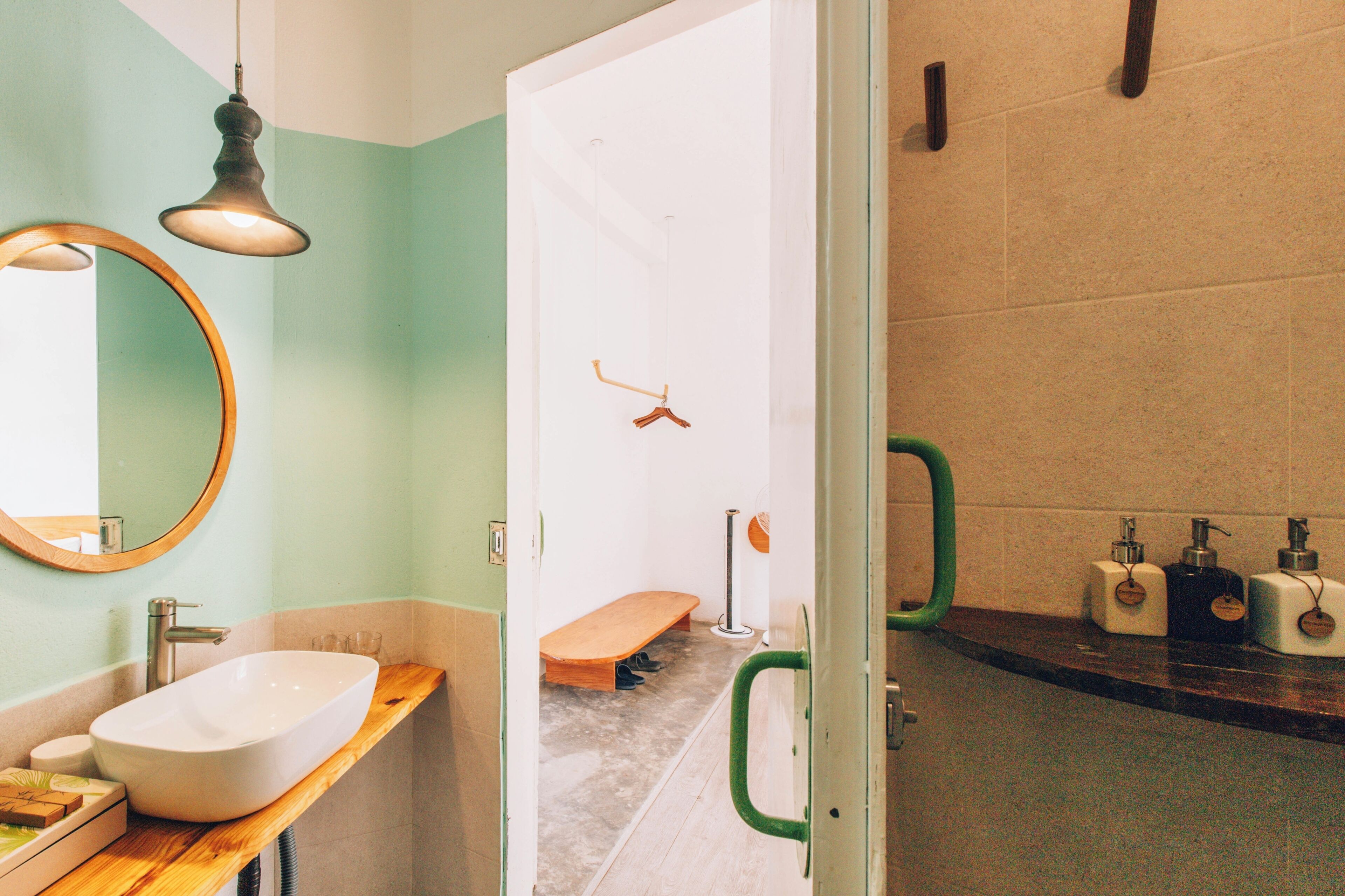 Une salle de bain avec un meuble-lavabo en bois, un grand miroir, un lavabo blanc, un banc et un espace douche.