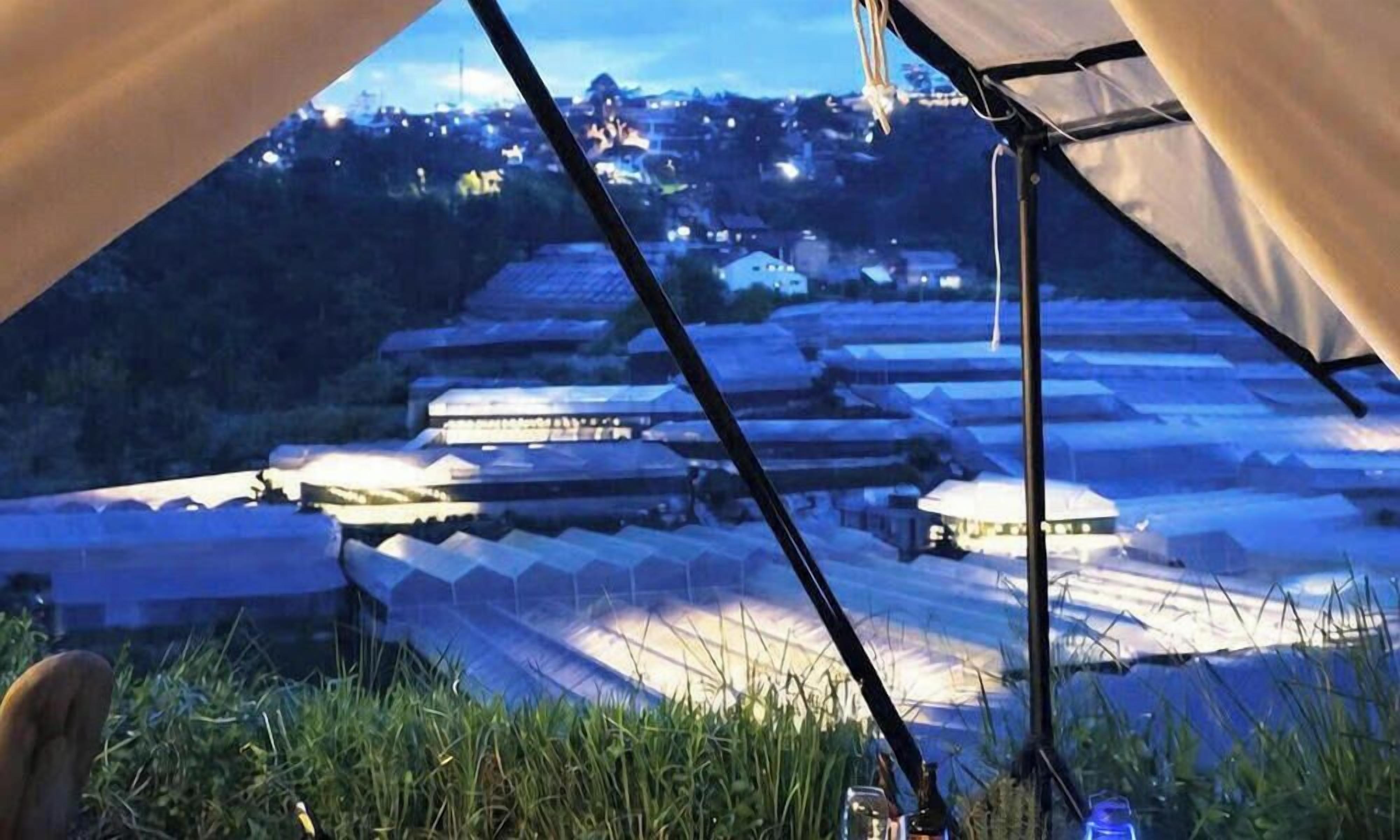 A tented area with a view of a cityscape at dusk.