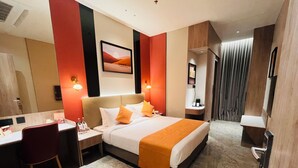 Een hotelkamer met een bed, bureau, stoel en een schilderij aan de muur.