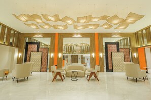 A lobby with a seating area, a reception desk, and a decorative ceiling. - Ira By Orchid Bhavnagar (Bhavnagar)