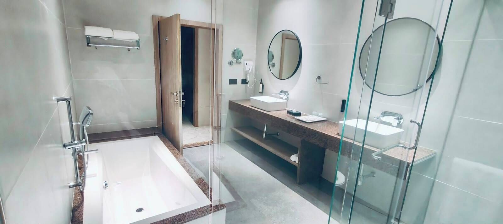 A modern bathroom with a glass shower enclosure, a large bathtub, and a vanity with a mirror.
