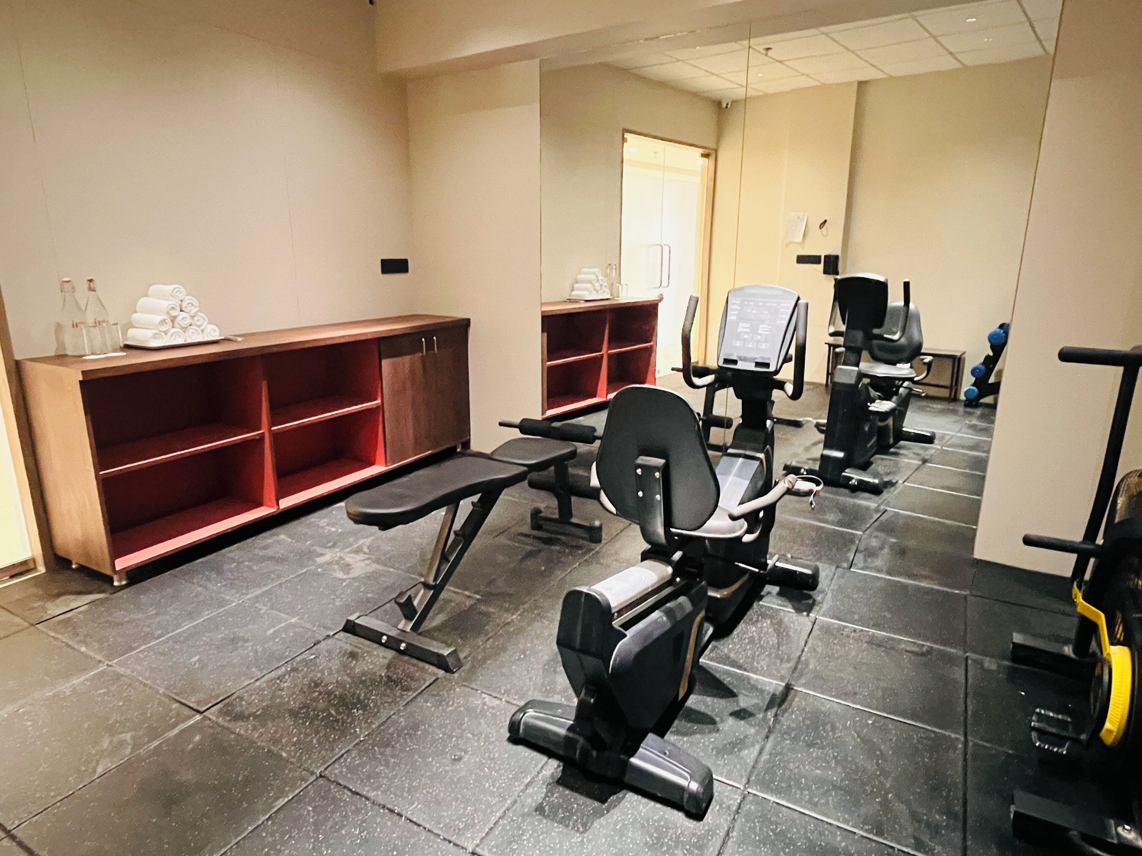 A gym with exercise equipment, benches, and a tiled floor.