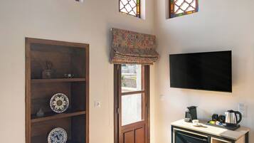 Habitación de hotel con cama, televisión, kitchenette pequeño y tres ventanas de arco.