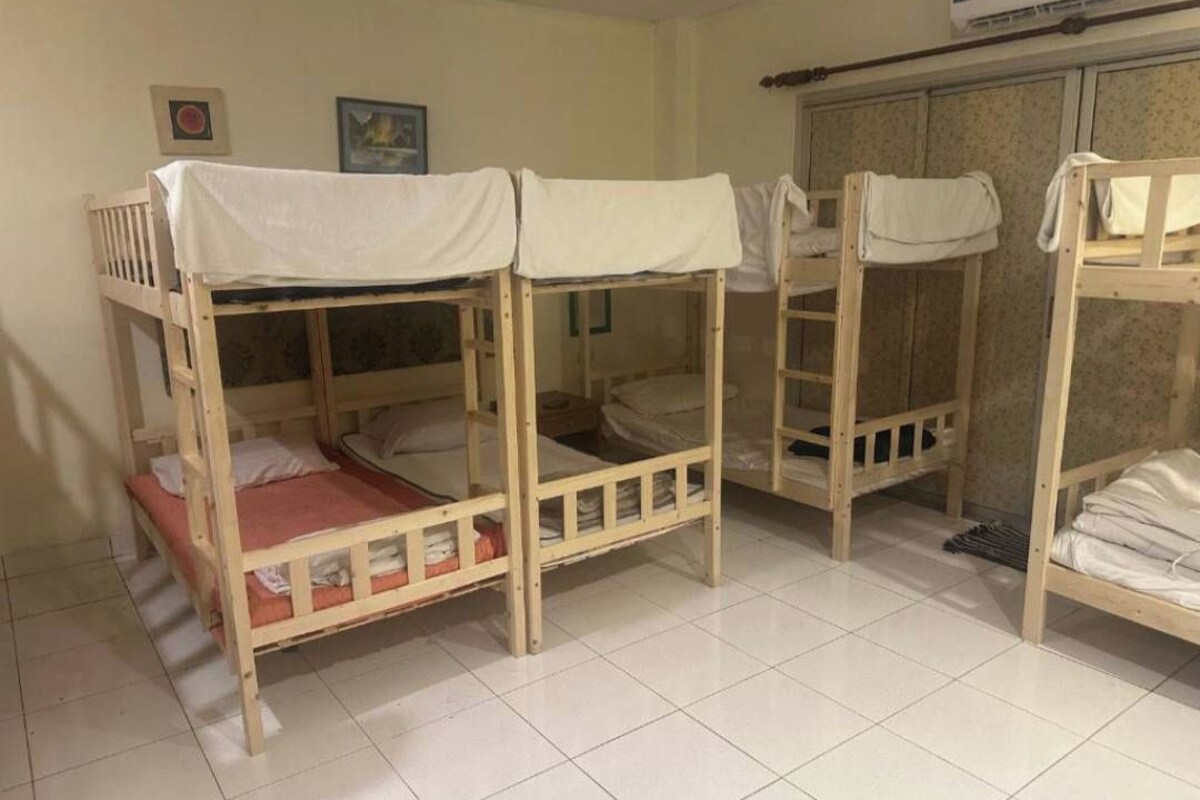 Una habitación con literas, suelo de baldosas, un armario y un cuadro en la pared.