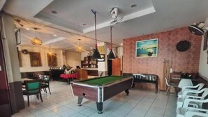 Een pooltafel in een ruimte met een eethoek, een bar en een dartbord aan de muur.