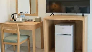 Habitación de hotel pequeña con escritorio de madera, televisor y refrigerador.