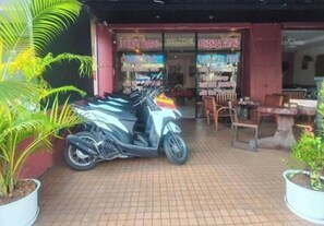 Una fachada con un letrero que dice 'WELCOME' y 'BONANZA PATONG'. Varias motocicletas están estacionadas afuera, y se ve la entrada.