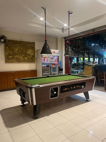 A pool table in a room with a ceiling fan, a wall mural, and a vending machine.