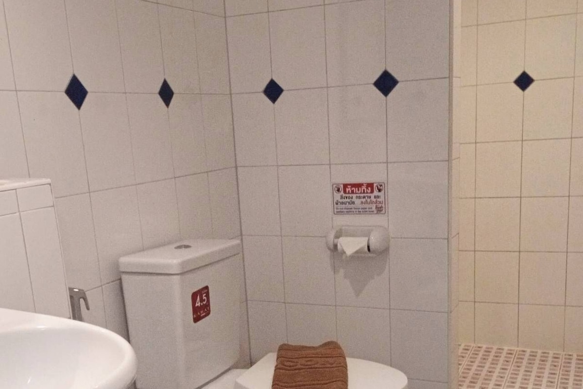 A bathroom with a toilet, a sink, and a trash bin.