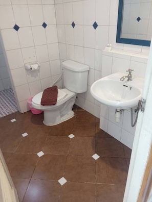 A bathroom with a toilet, sink, and tiled floor. - Bursa Hotel (Patong)