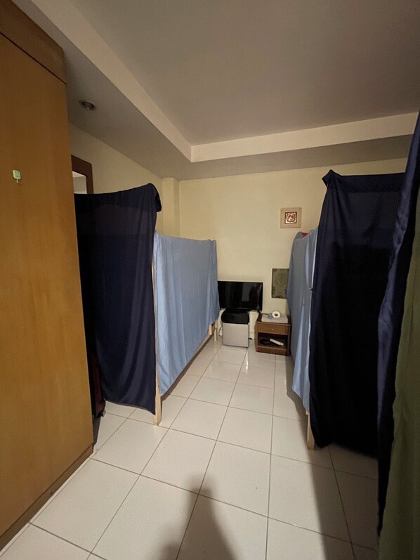 Un pasillo con dos camas, un televisor y una mesita.