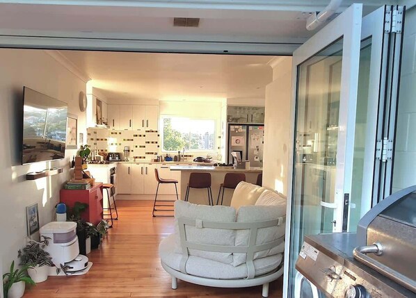 A modern kitchen with white cabinets, a central island, and a dining area with a white sofa.