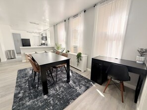 Eine moderne Küche mit Essbereich, ausgestattet mit einem schwarzen Esstisch, Stühlen und einem schwarzen Schreibtisch.