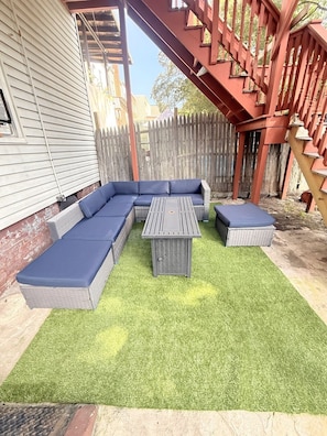 Ein Garten mit einer Eckcouch, einem kleinen Tisch und einer Holzterrasse.