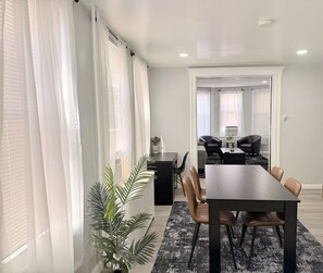 A modern dining area with a dark wooden table and leather chairs, a black and white rug, and a potted plant. - New Modern JC Gem w/ On-Site Parking • Minutes to NYC, EWR & MetLife • Sleeps 6 (Jersey City)