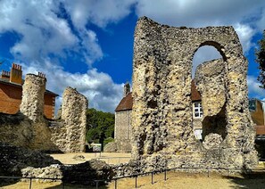 A historic stone structure with a large archway, surrounded by modern buildings and a clear sky. - Free Parking Central Reading Flat Fully Equipped (Berkshire)