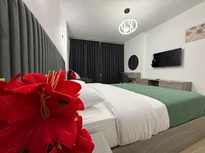 Ein modernes Schlafzimmer mit einem Bett, einem Flachbildfernseher, einem Schreibtisch und einem großen Fenster mit Vorhängen.