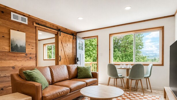 A cozy room with a brown leather sofa, a round wooden coffee table, and a checkered floor. - NEW Cabin Olympus: Starlink, Firepit, BBQ (Beaver)