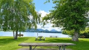 A picnic area with a table and benches, surrounded by trees and a lake with mountains in the background. - NEW Cabin Olympus: Starlink, Firepit, BBQ (Beaver)