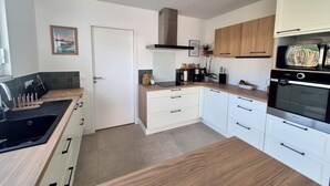Une cuisine moderne avec des meubles blancs, une cuisinière noire et un plan de travail en bois.