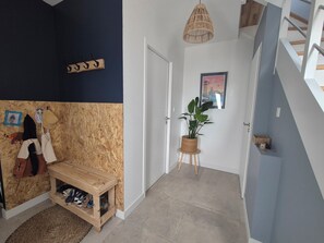 A hallway with a wooden bench, a potted plant, a coat rack, and a framed picture on the wall. - Family home in the village (Guidel)