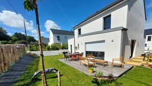 Une maison moderne dotée d’un patio, d’une terrasse en bois et d’une cour clôturée.