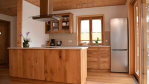 Una cuina moderna amb armaris de fusta, una illa central, forn de sobre i finestra que deixa entrar llum natural.