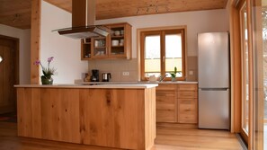 Eine moderne Küche mit Holzschränken, einer Mittelinsel, einem Einbauofen und einem Fenster für natürliches Licht.