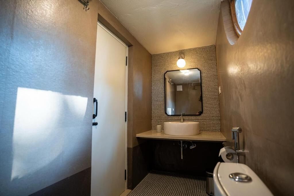 Une petite salle de bain avec un lavabo blanc, un miroir et des toilettes.