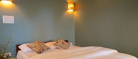 A bedroom with a bed, two wall-mounted lamps, and a power outlet on the wall.