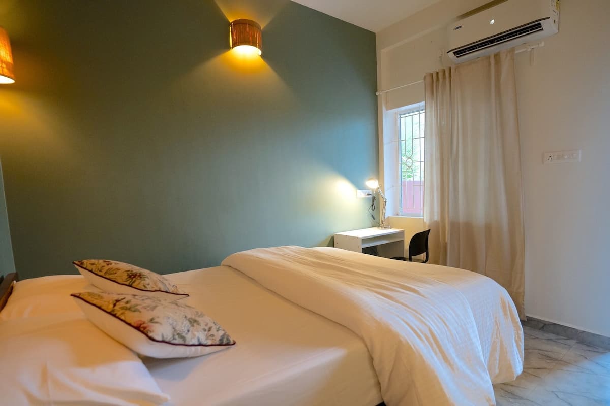 Une chambre à coucher comprenant un lit, un bureau, une chaise, une lampe et un appareil de climatisation.