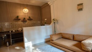A modern living room with a sofa, a coffee table, and a kitchen area with a counter and shelves. - Wonderland  (Mandrem pernem)