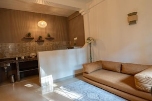 A modern living room with a sofa, a coffee table, and a kitchen area with a counter and shelves. - Wonderland  (Mandrem pernem)