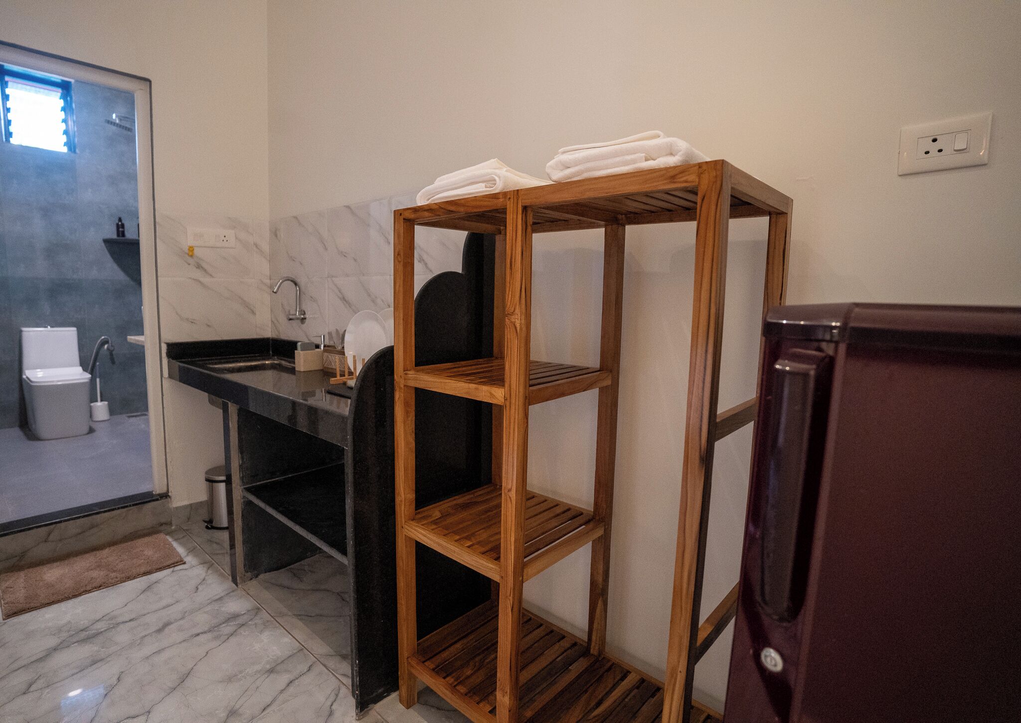 Un baño con un estante de madera, un lavamanos, un inodoro y un espejo.