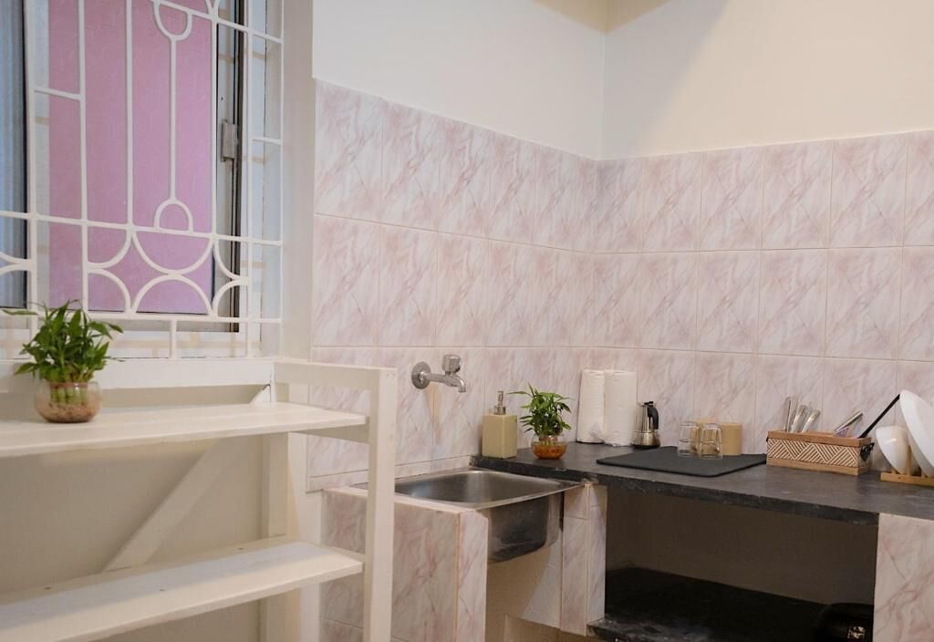Une cuisine équipée d’un évier, d’un plan de travail et d’une fenêtre ornée d’une grille décorative.