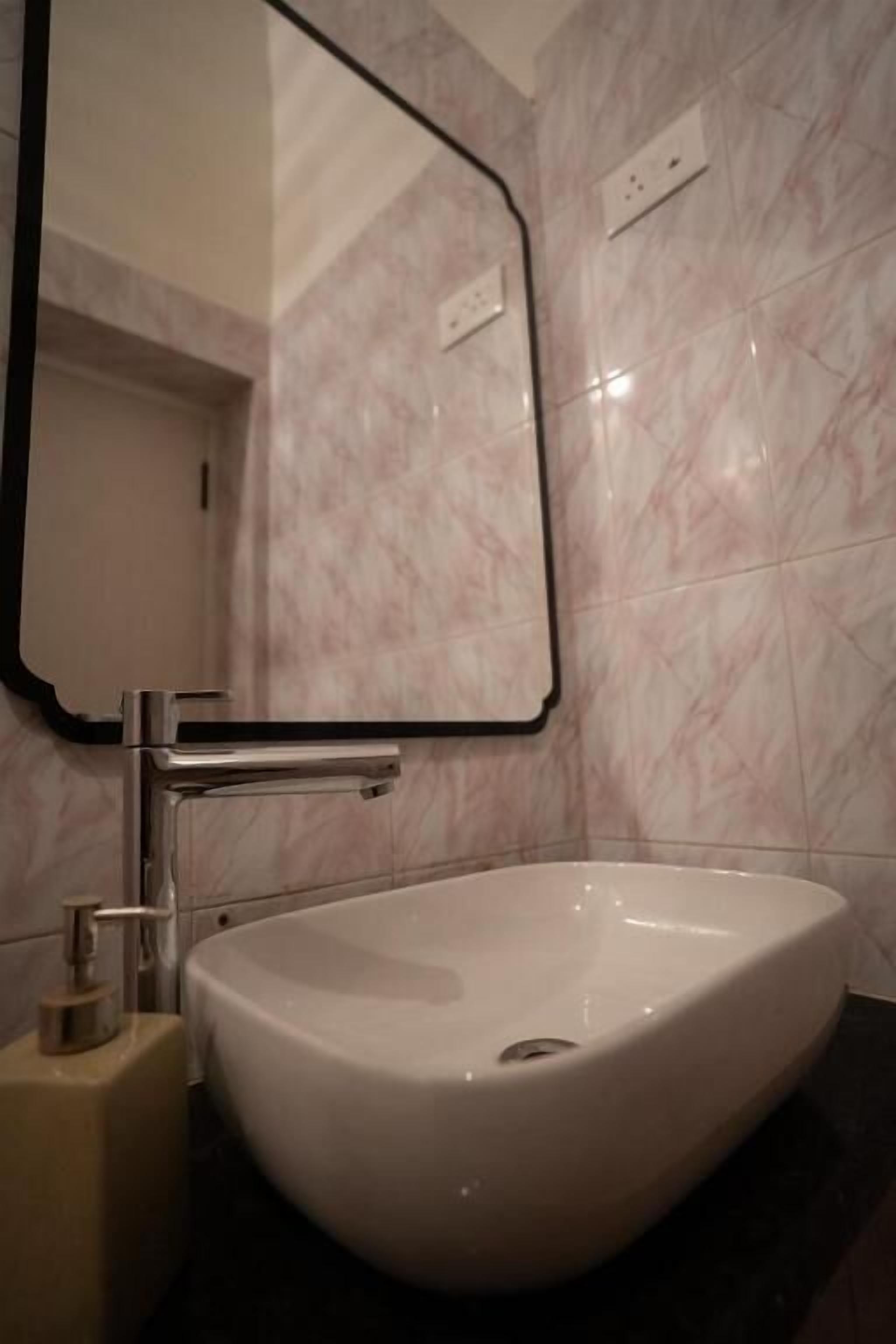 Une salle de bain avec un lavabo blanc, un miroir et des murs en marbre.