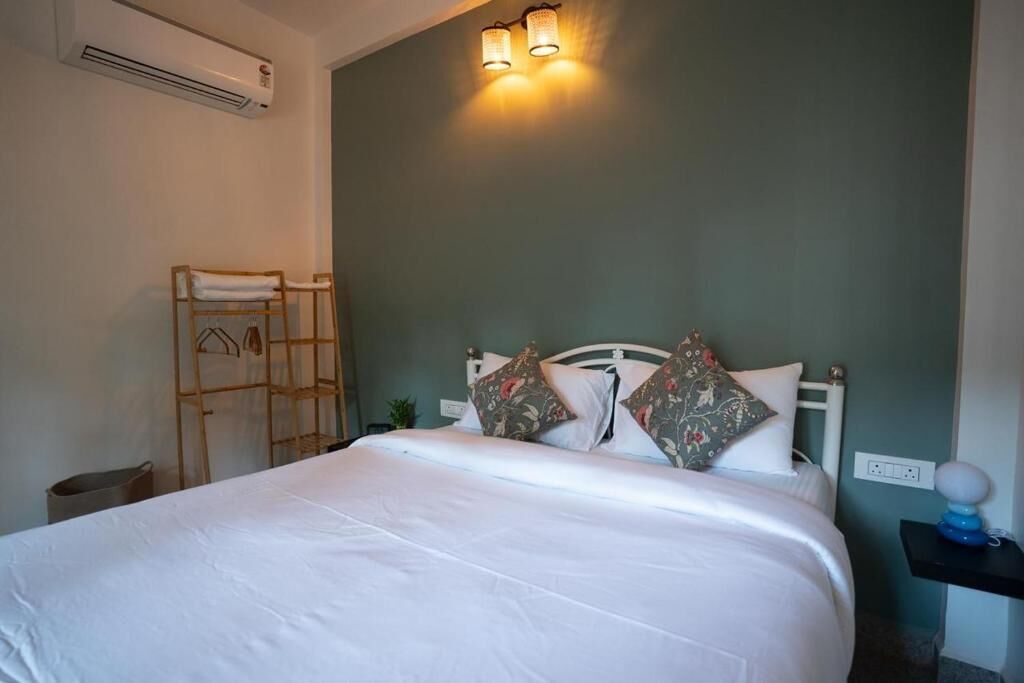 A neatly made bed with white bedding, a wooden ladder, and a wall-mounted air conditioner.