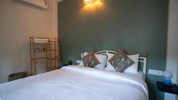 A neatly made bed with white bedding, a wooden ladder, and a wall-mounted air conditioner.