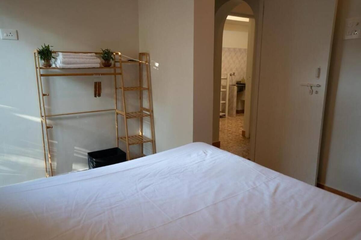 Un dormitorio con cama, una escalera de madera y un pequeño cubo de basura negro.