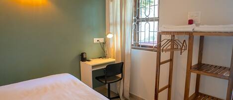 Un dormitorio con cama, escritorio, silla y estantería de madera.