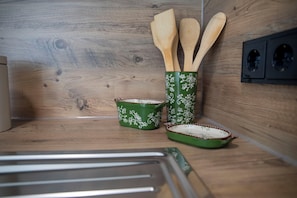 A kitchen with wooden cabinets, a green and white patterned container holding wooden utensils, and a green and white patterned baking dish.