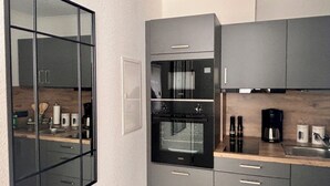 Une cuisine moderne équipée d’un four encastré, d’une machine à café et d’un four à micro-ondes.
