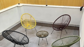 Una terraza en la azotea con cinco sillas de metal y una pequeña mesa redonda.